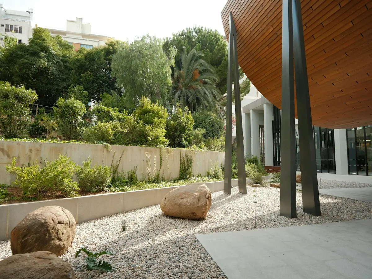 Jardin minéral avec gros blocs de pierre et gravier clair devant un bâtiment