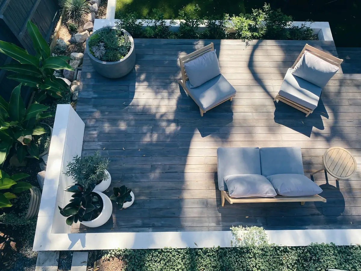 Terrasse en bois vue du dessus avec chaises longues et bacs de plantes